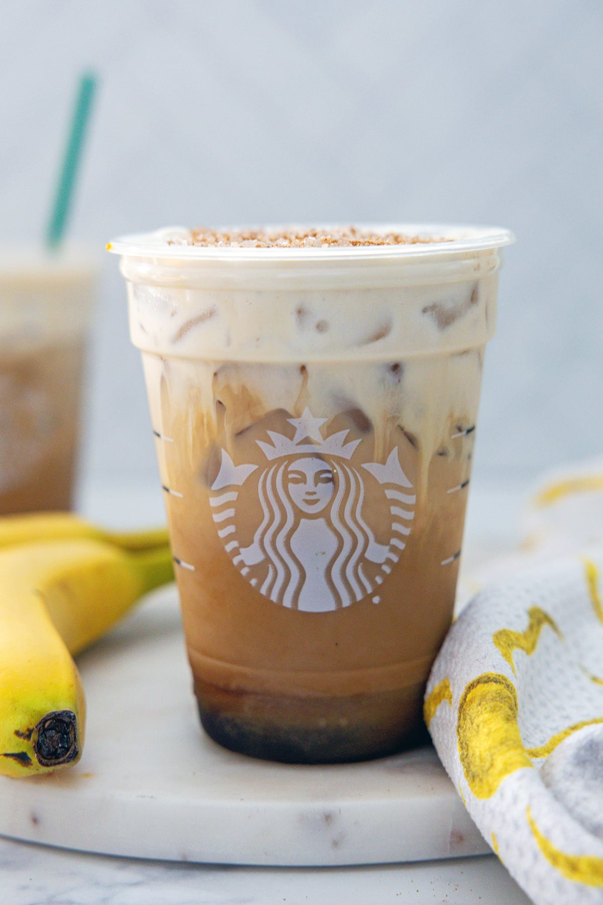Head-on view of an Iced Banana Bread Latte with bananas in the background.