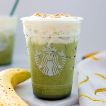 Head-on closeup view of an Iced Banana Bread Matcha drink topped with cold foam.