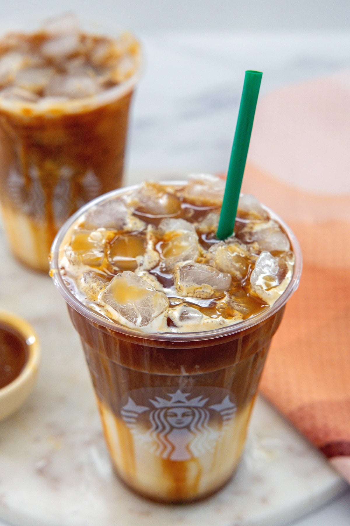 Overhead view of an Iced Caramel Macchiato with green straw.