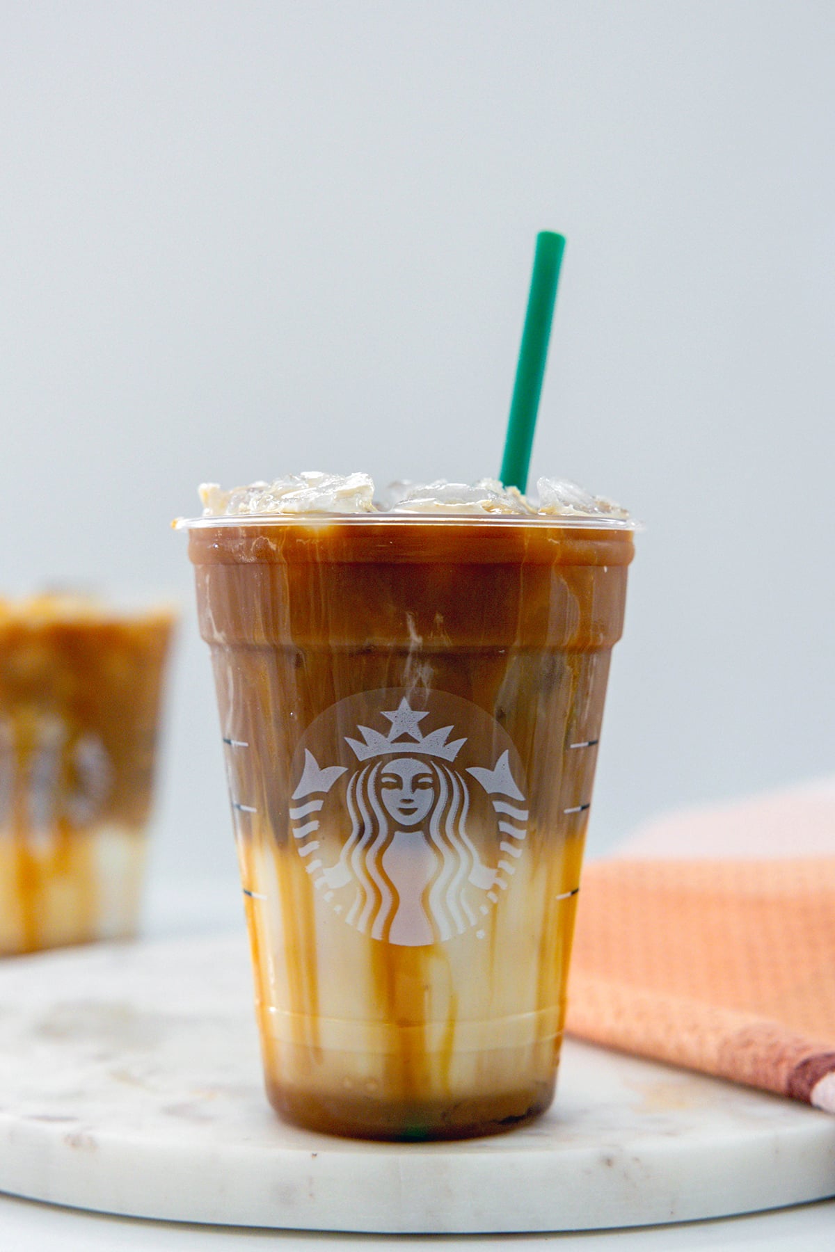 Head-on view of an Iced Caramel Macchiato in a Starbucks cup with green straw.