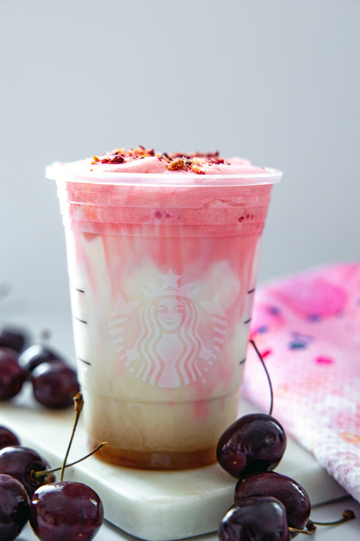 Head-on view of an iced Cherry Chai Latte with fresh cherries all around.