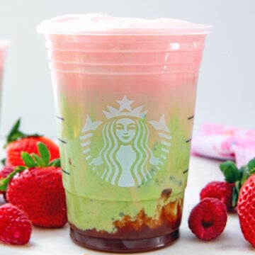 Head-on closeup view of a Starbucks Iced Double Berry Matcha with strawberries and raspberries all around.