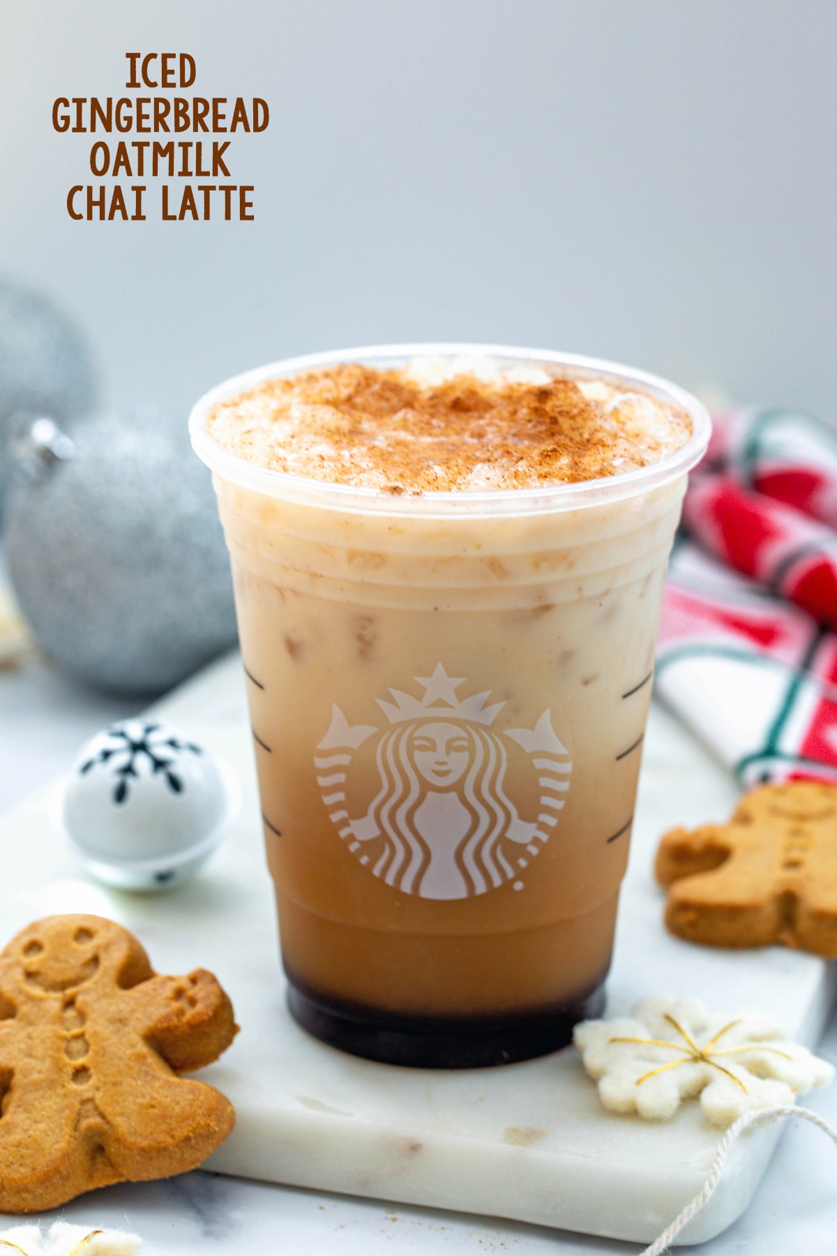 Iced Gingerbread Oatmilk Chai Latte in a Starbucks cup with gingerbread men cookies around and recipe title at top.
