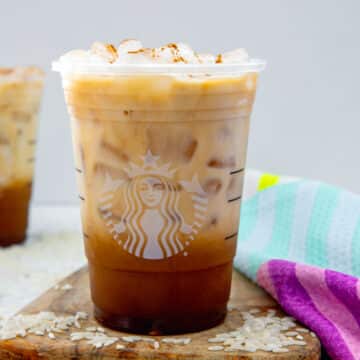 Closeup view of a Horchata Shaken Espresso in a Starbucks cup with white rice all around.