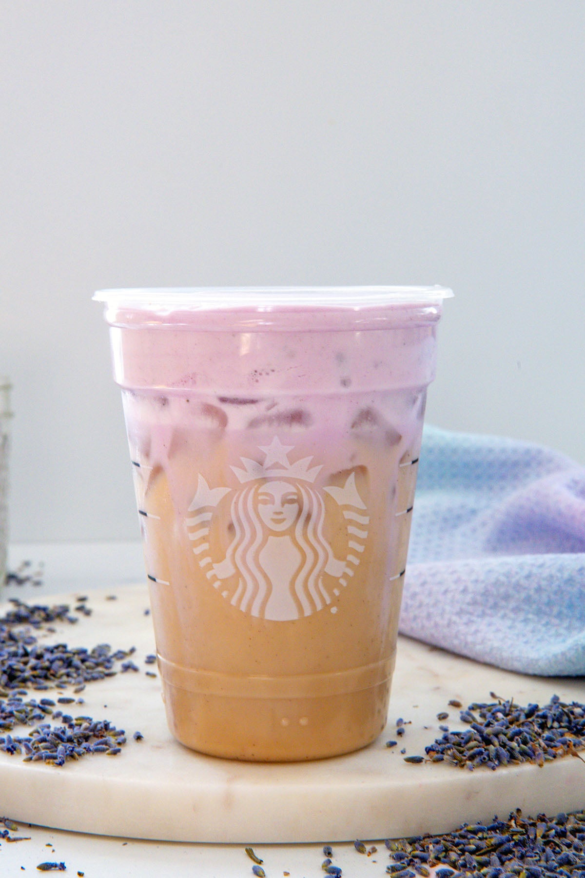 Closeup view of an Iced Lavender Cream Chai with lavender flowers all around.