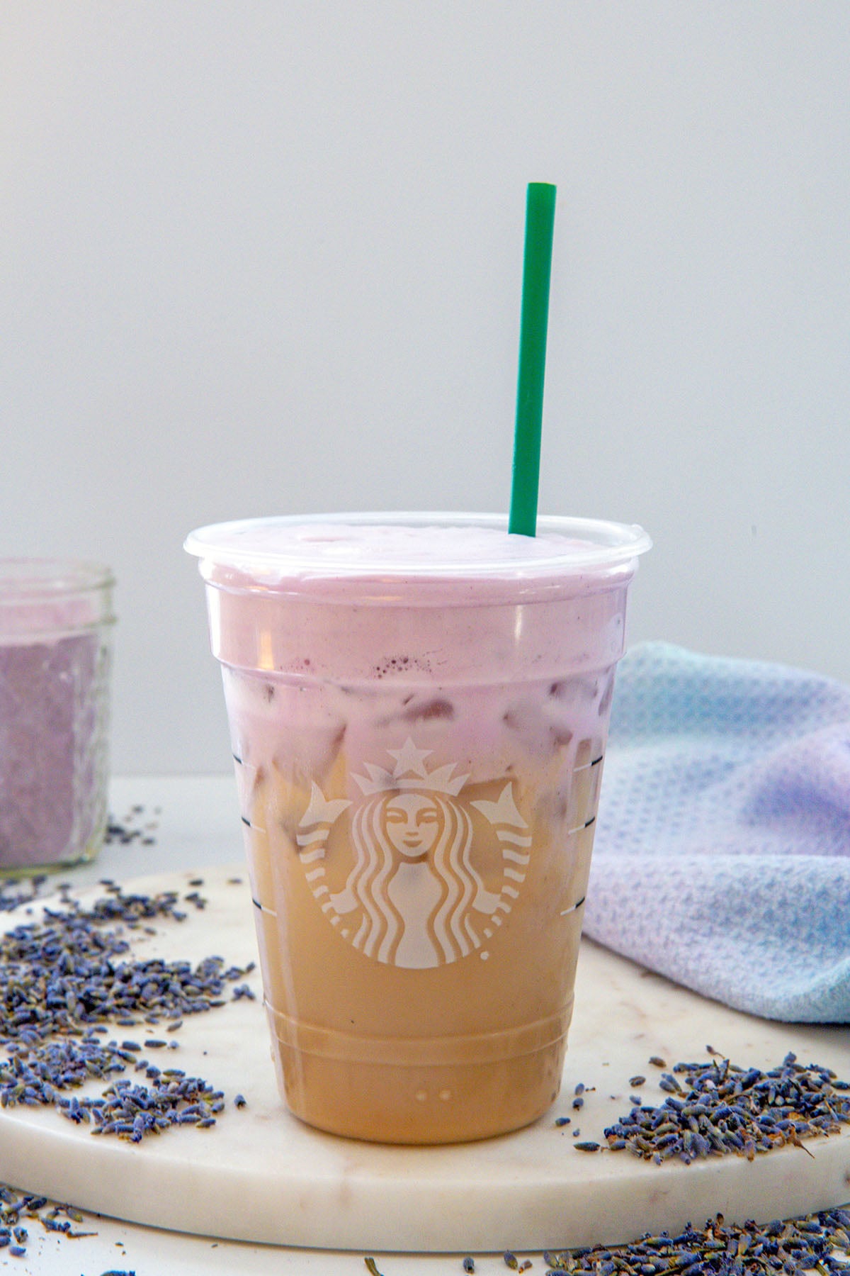 Head-on view of an iced chai with lavender cold foam with green straw and recipe title at top.