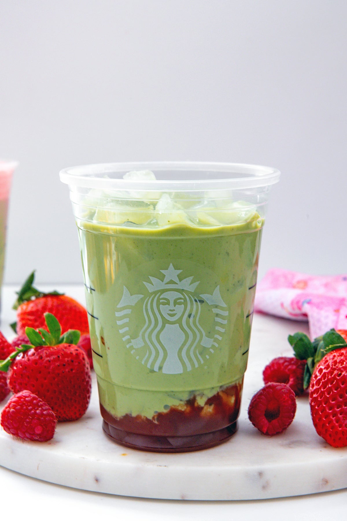 Starbucks cup with strawberry puree on the bottom and matcha and milk on top.