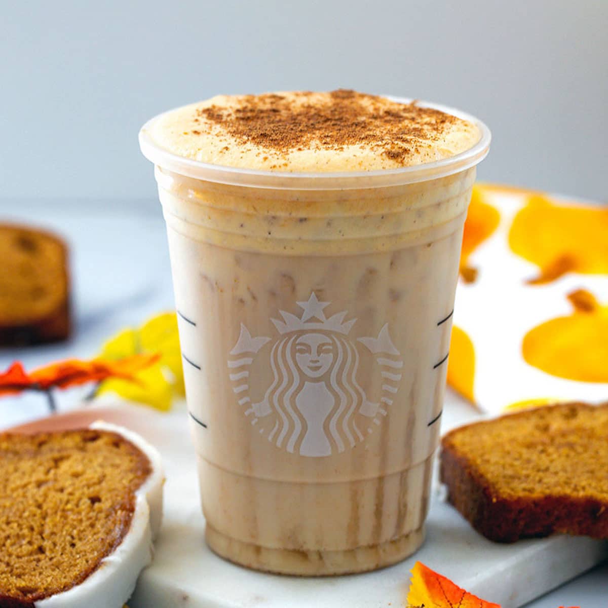 Head-on of an Iced Pumpkin Cream Chai Tea Latte with pumpkin bread all around.