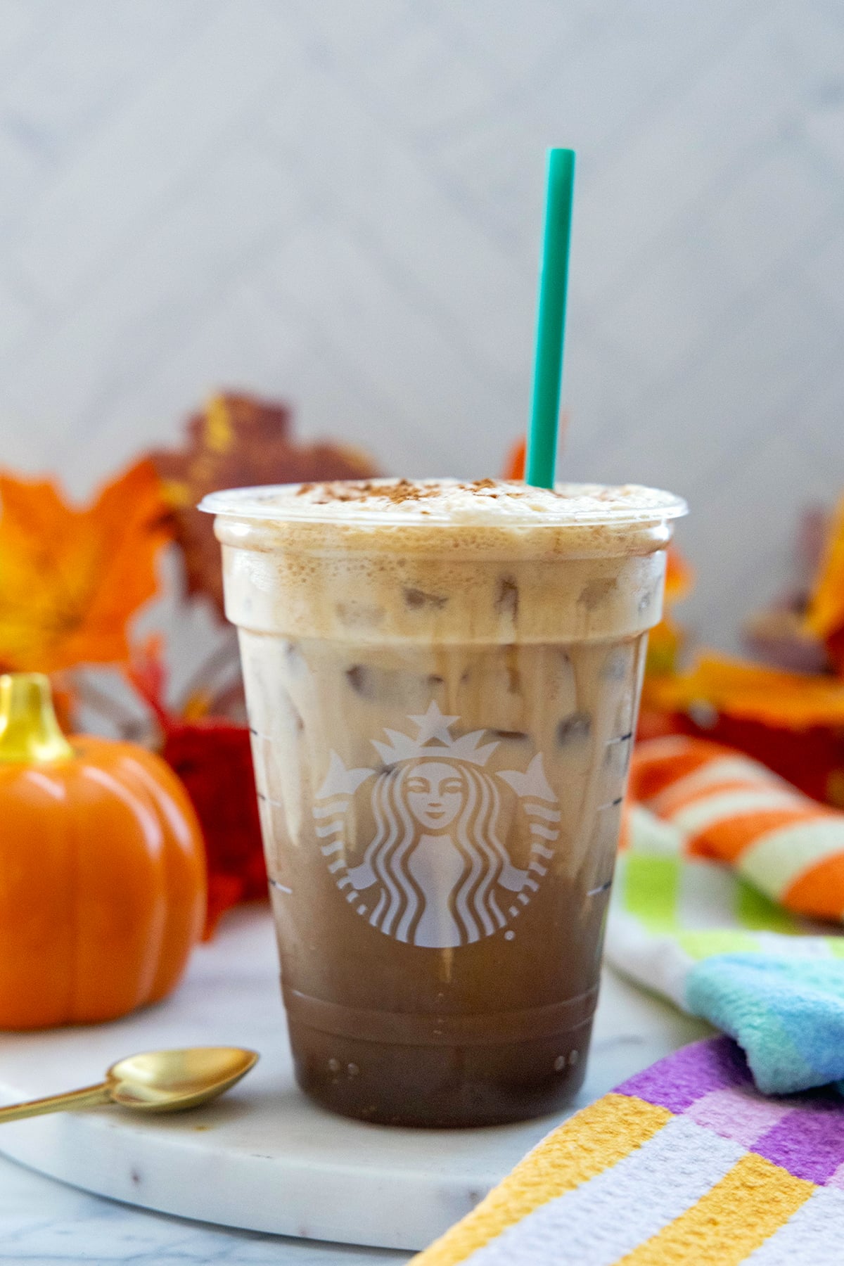 Head-on view of an Iced Pumpkin Cream Shaken Espresso in a Starbucks cup with green straw.