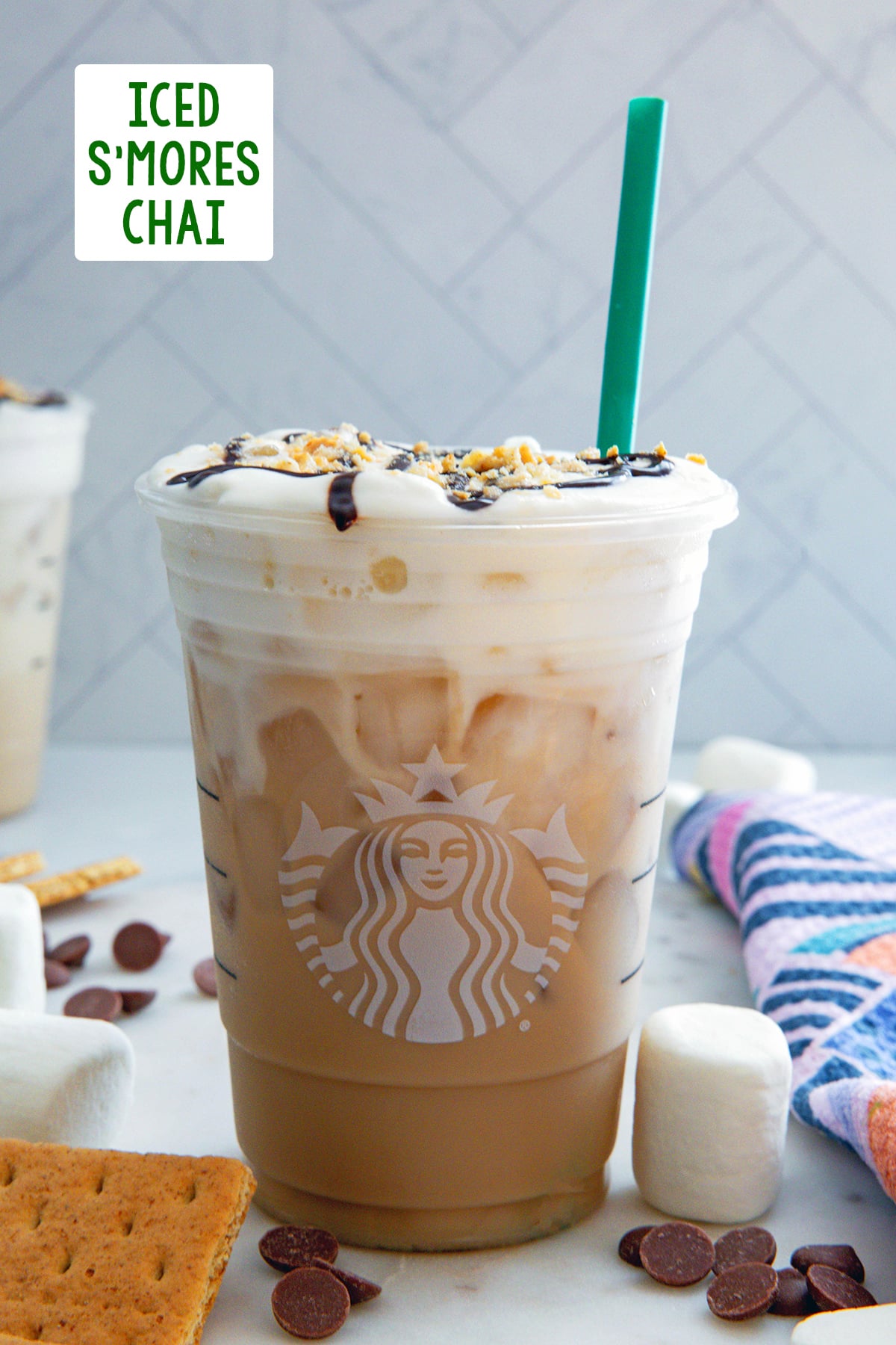 Head-on view of an Iced S'mores Chai with graham crackers, chocolate, and marshmallows all around and recipe title at top.