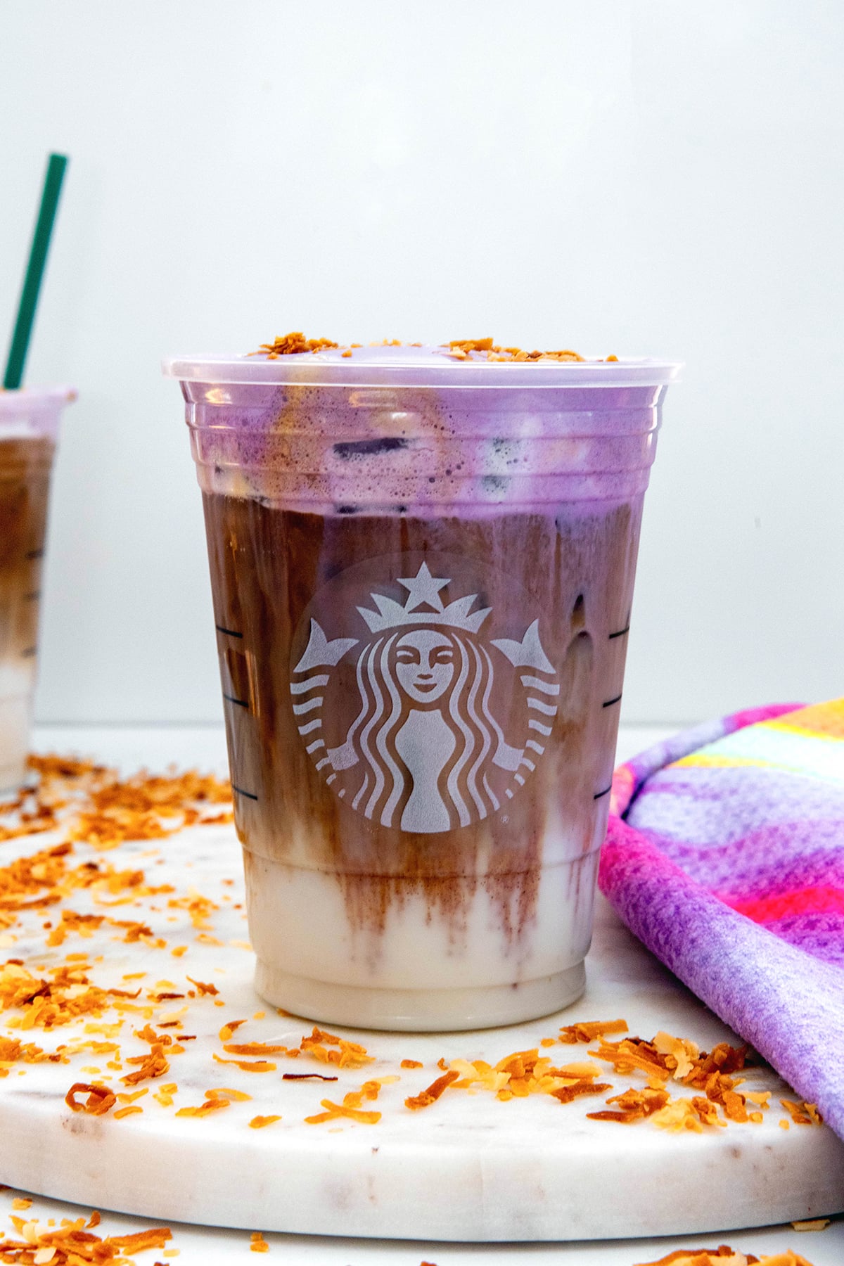 Head-on view of an Iced Ube Macchiato wit layer of milk, layer of espresso, and layer of ube coconut cold foam.