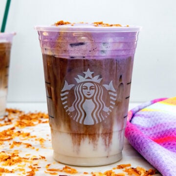 Closeup view of an Iced Ube Coconnut Macchiato with purple cold foam.