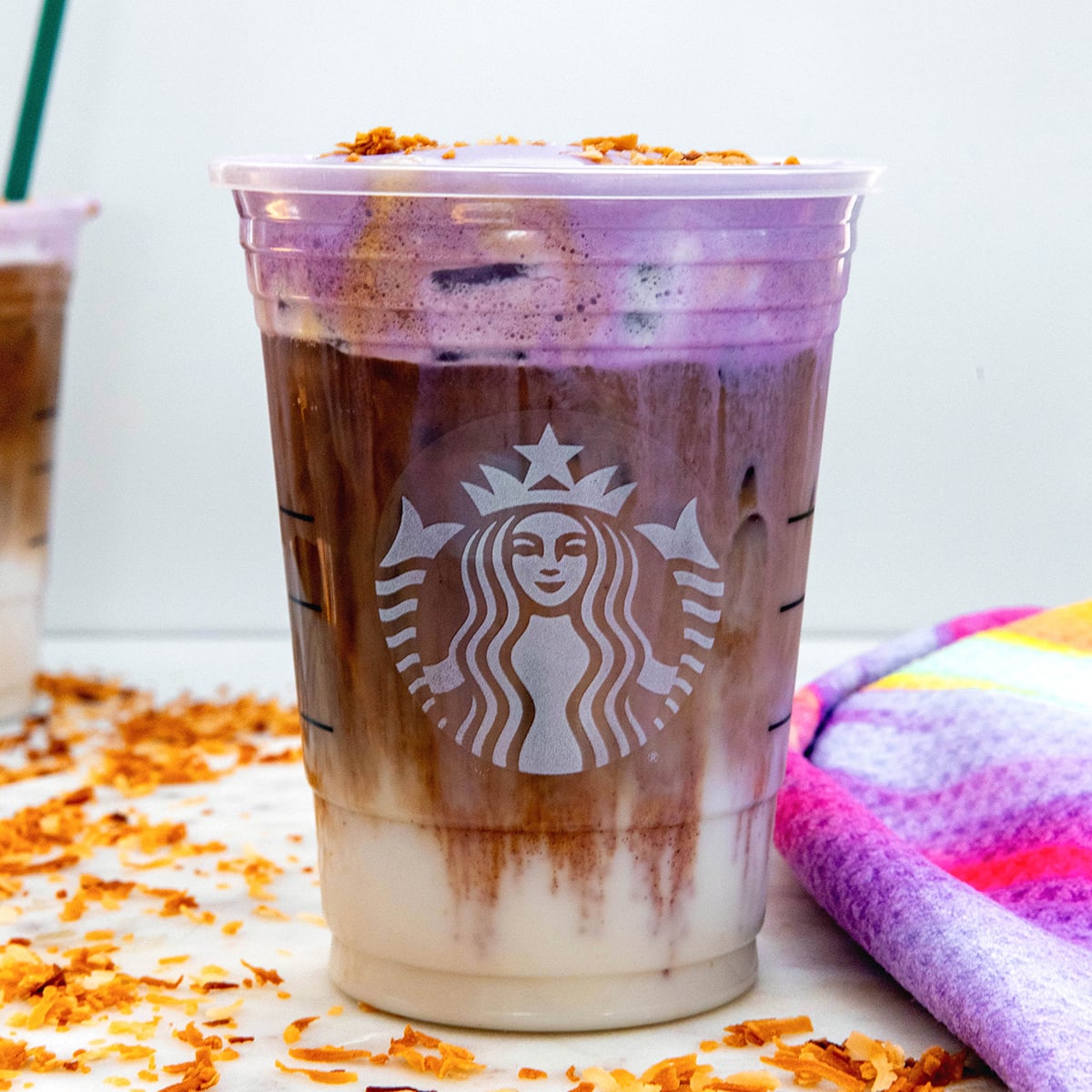 Closeup view of an Iced Ube Coconnut Macchiato with purple cold foam.