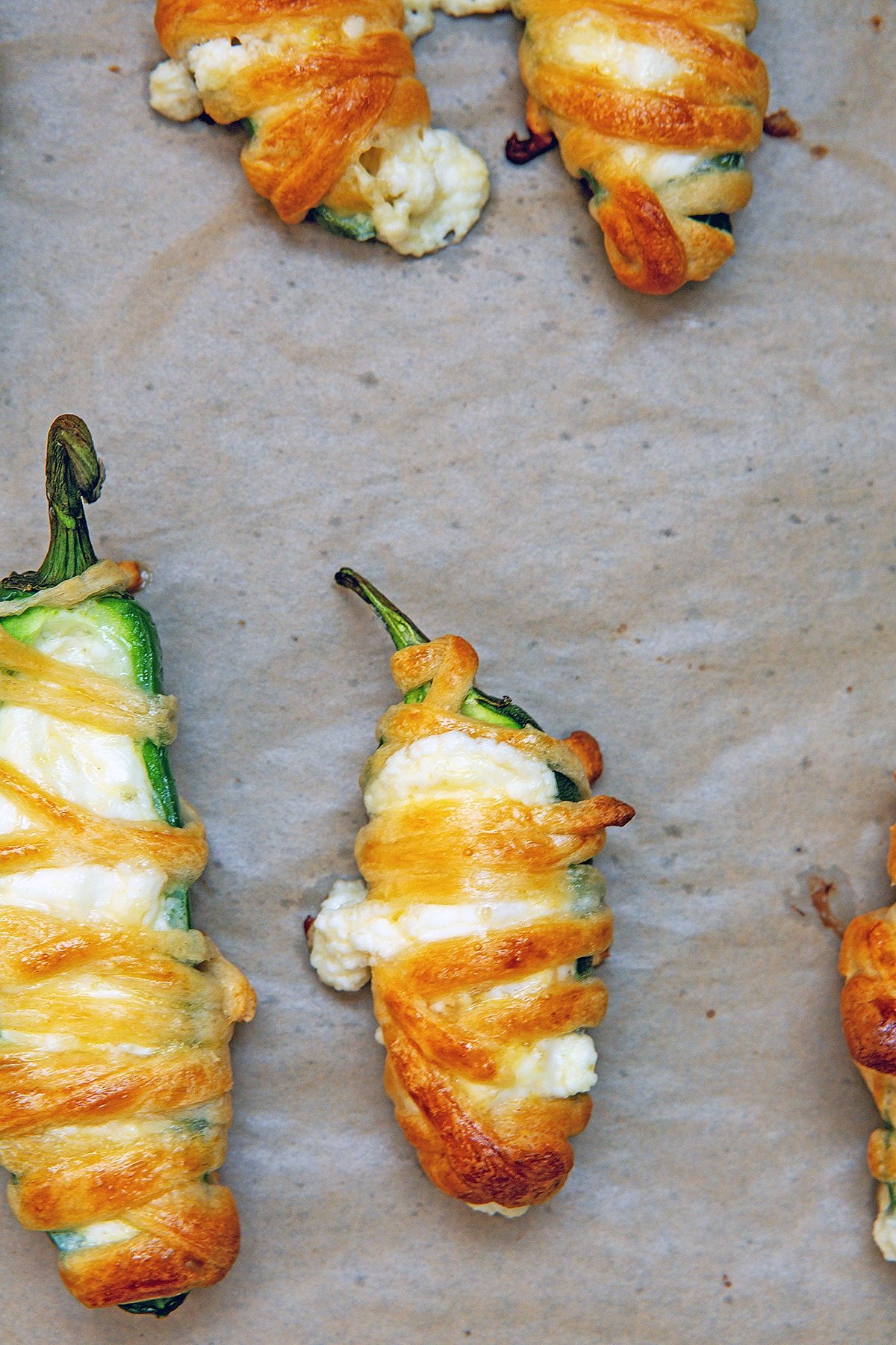 Jalapeño poppers with phyllo dough wrapped around them baked on baking sheet.