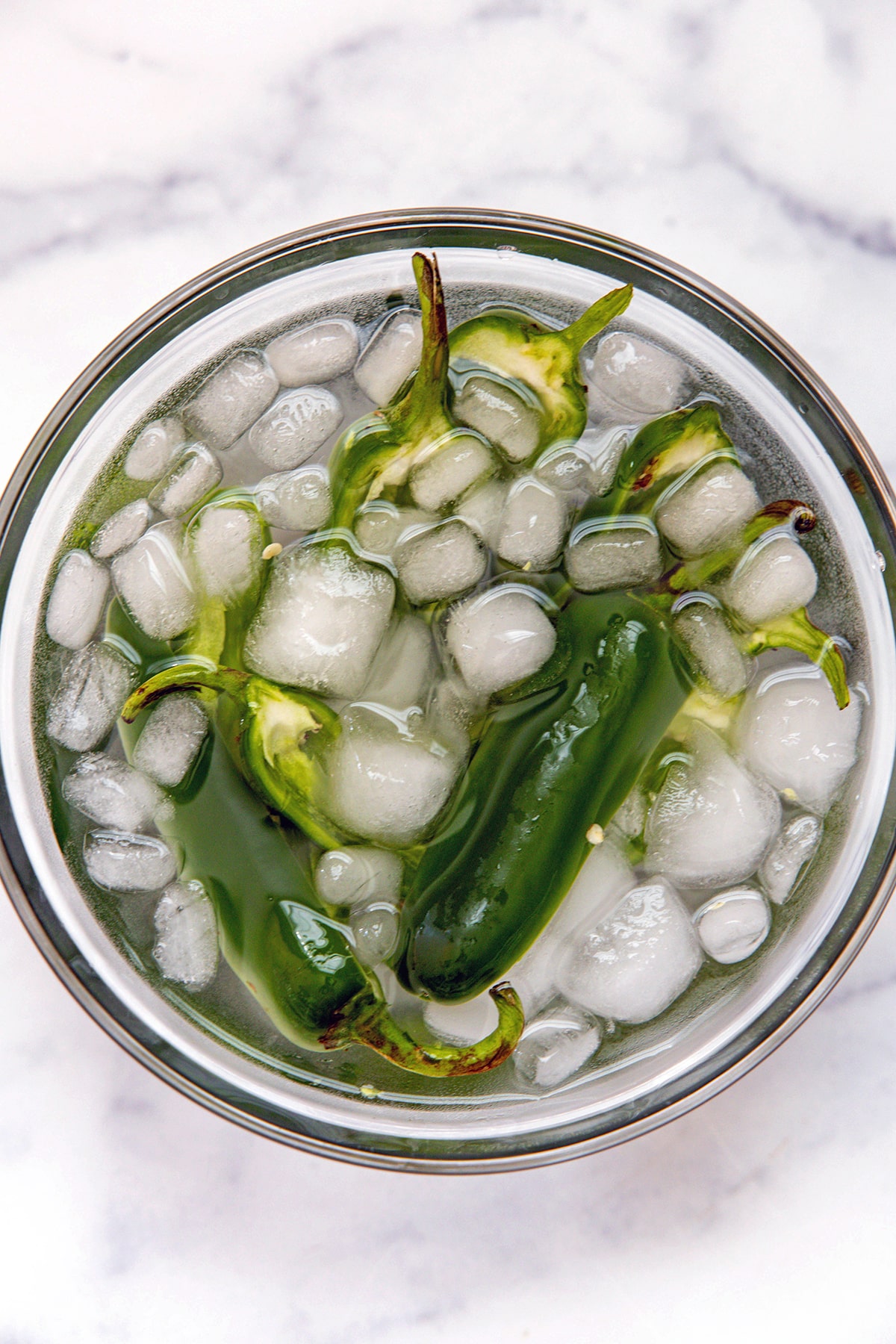 Halved jalapeño peppers soaking in ice water.