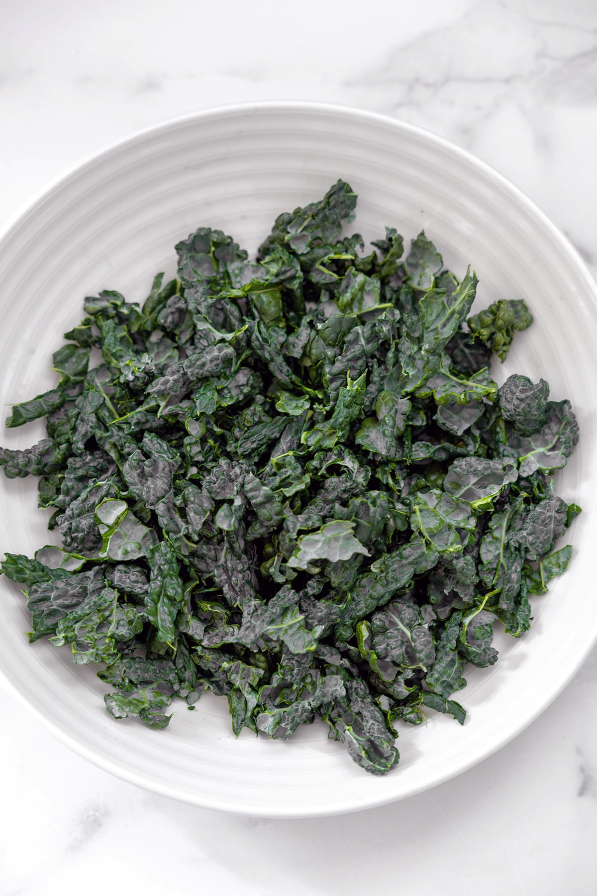 Roughly chopped kale in big white bowl.