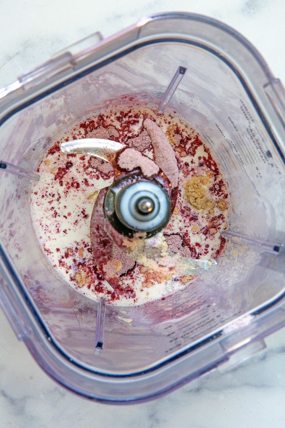 Overhead view of milk, xanthan gum, lavender powder, and vanilla syrup in blender.