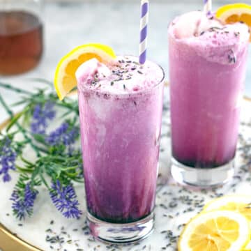 Close-up view of lavender lemonade floats with dried lavender and lemons all around.