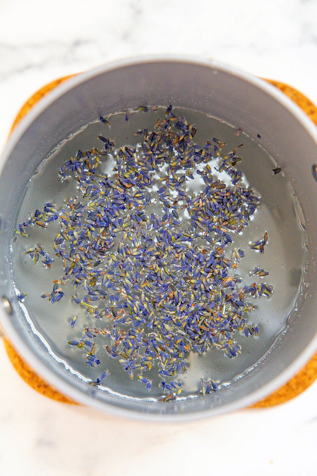 Overhead view of dried lavender in sugar water mixture in saucepan.