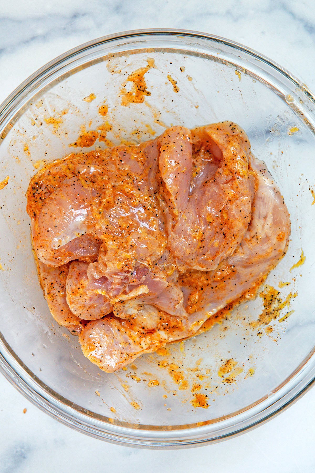 Chicken breasts marinating in bowl.