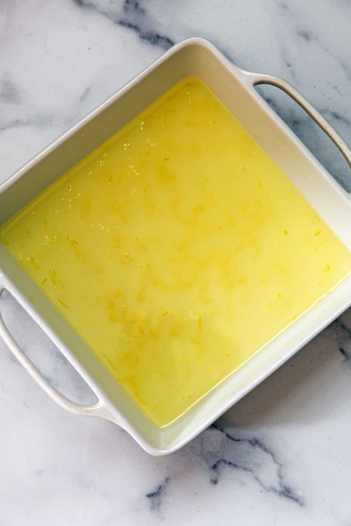 Lemon juice, zest, and simple syrup in a baking dish.