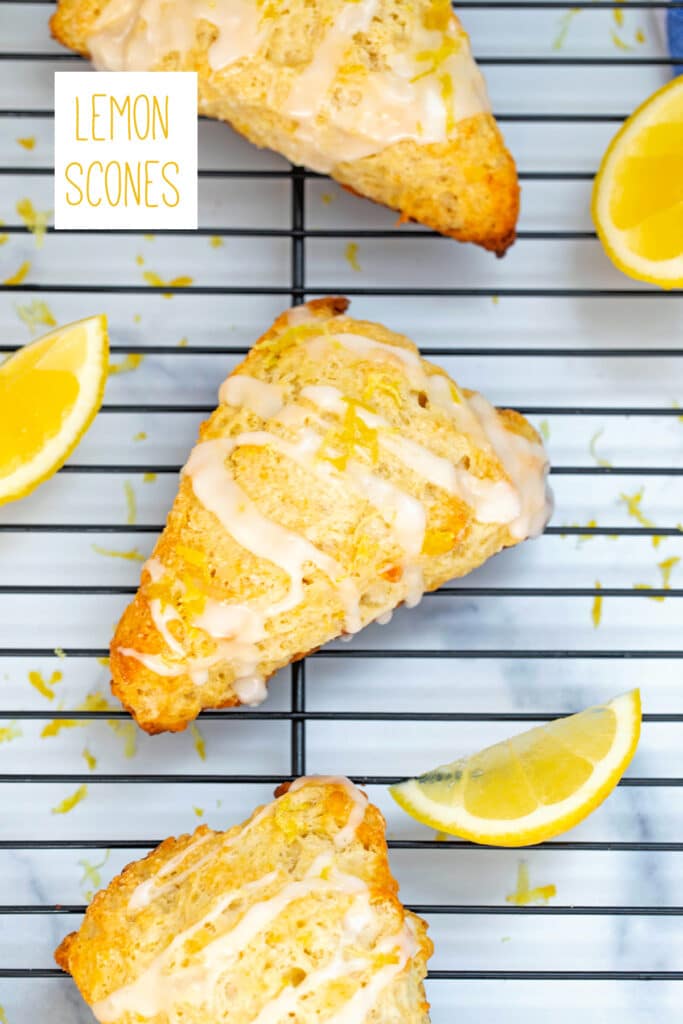 Overhead view of lemon scones with icing drizzle, lemon wedges all around, and recipe title at top.