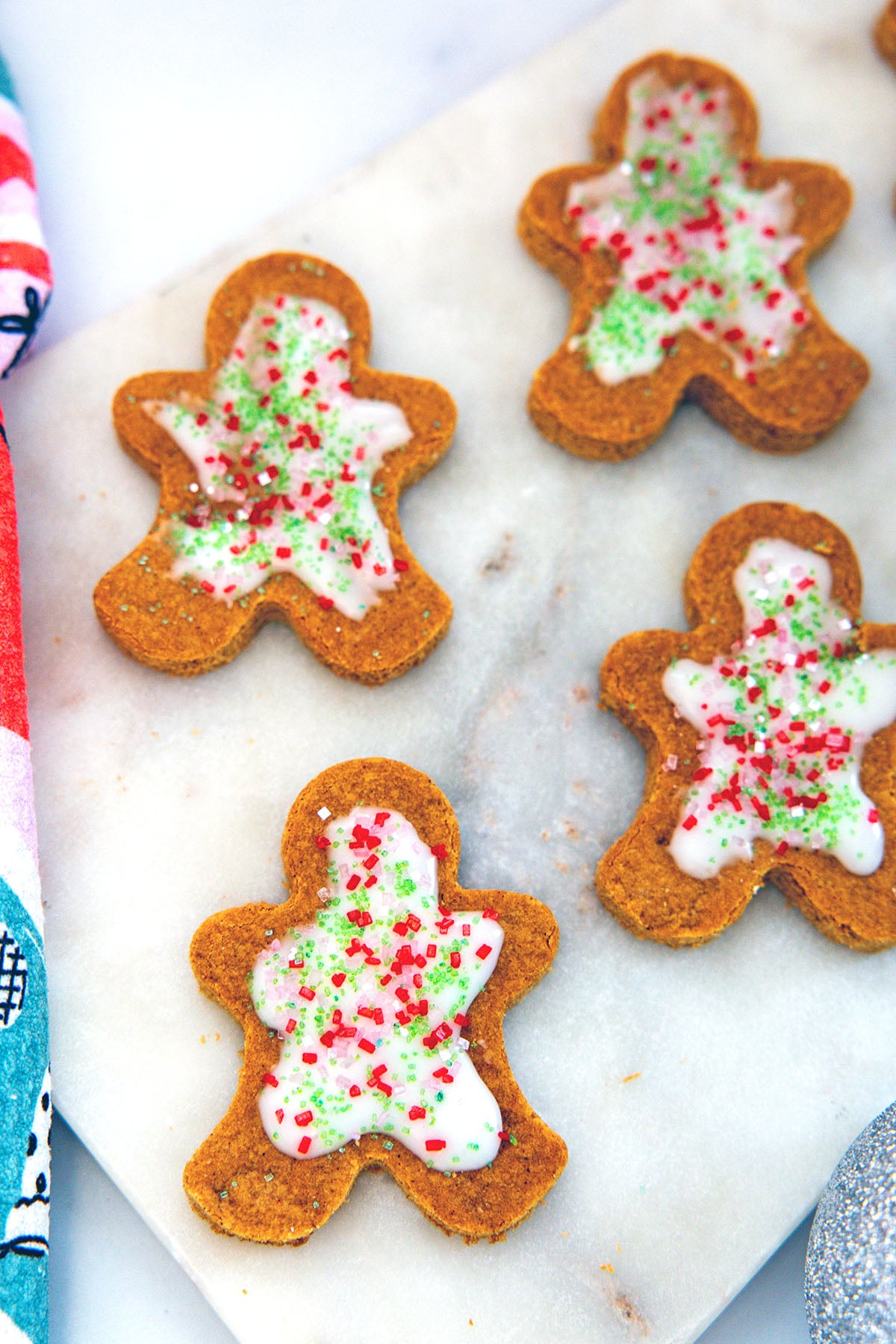 Overhead closeup of gingerbread men cookies frosted with vanilla icing and red and green sprinkles.