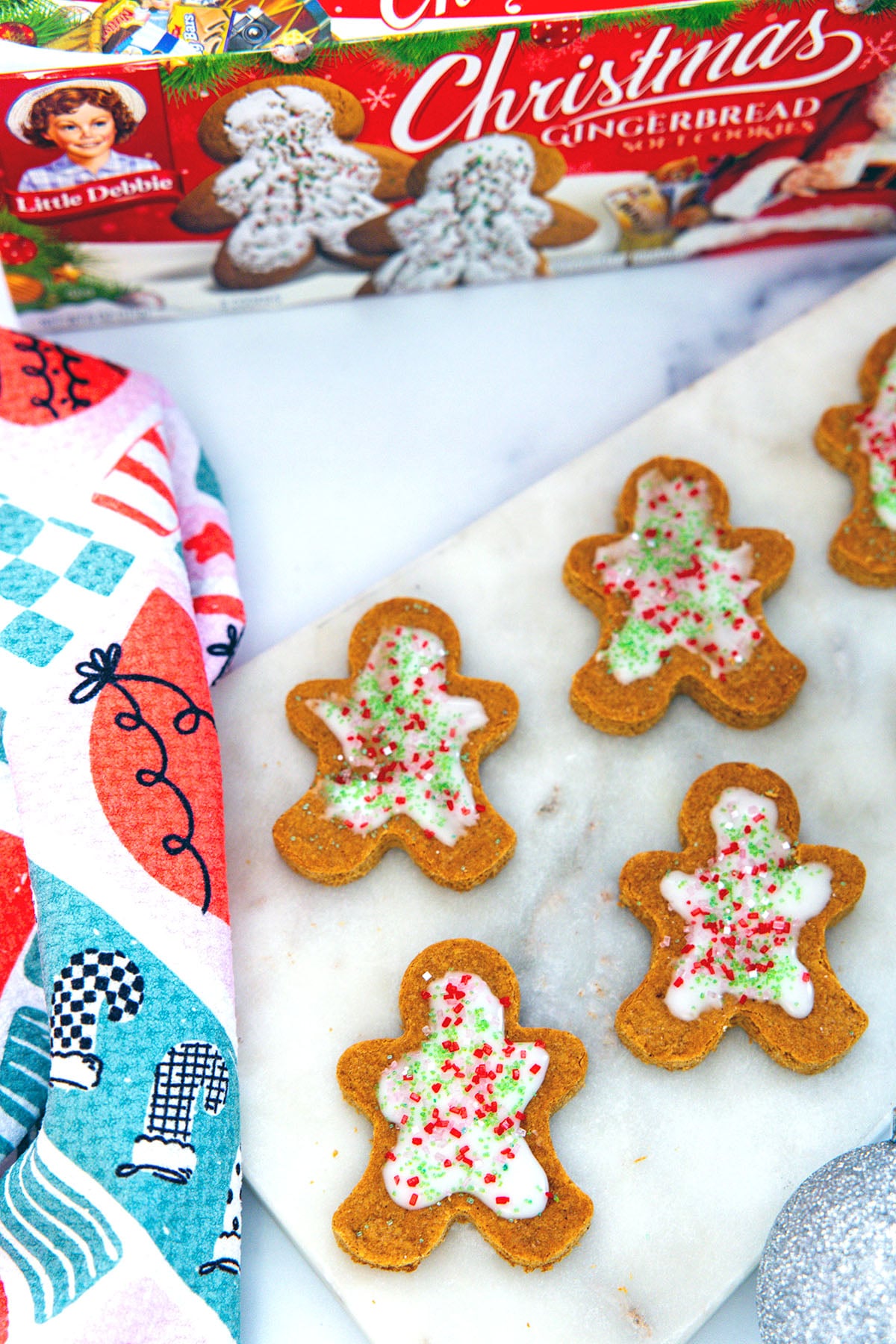 Overhead view of frosted gingerbread men cookies with box of cookies in background.