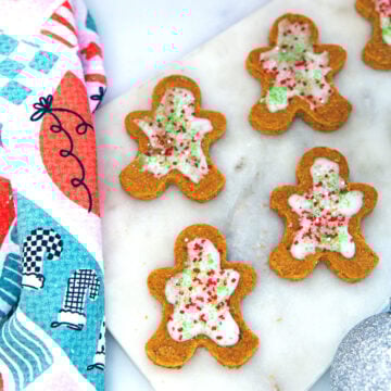 Overhead closeup view of gingerbread men with icing and sprinkles on a marble surface.