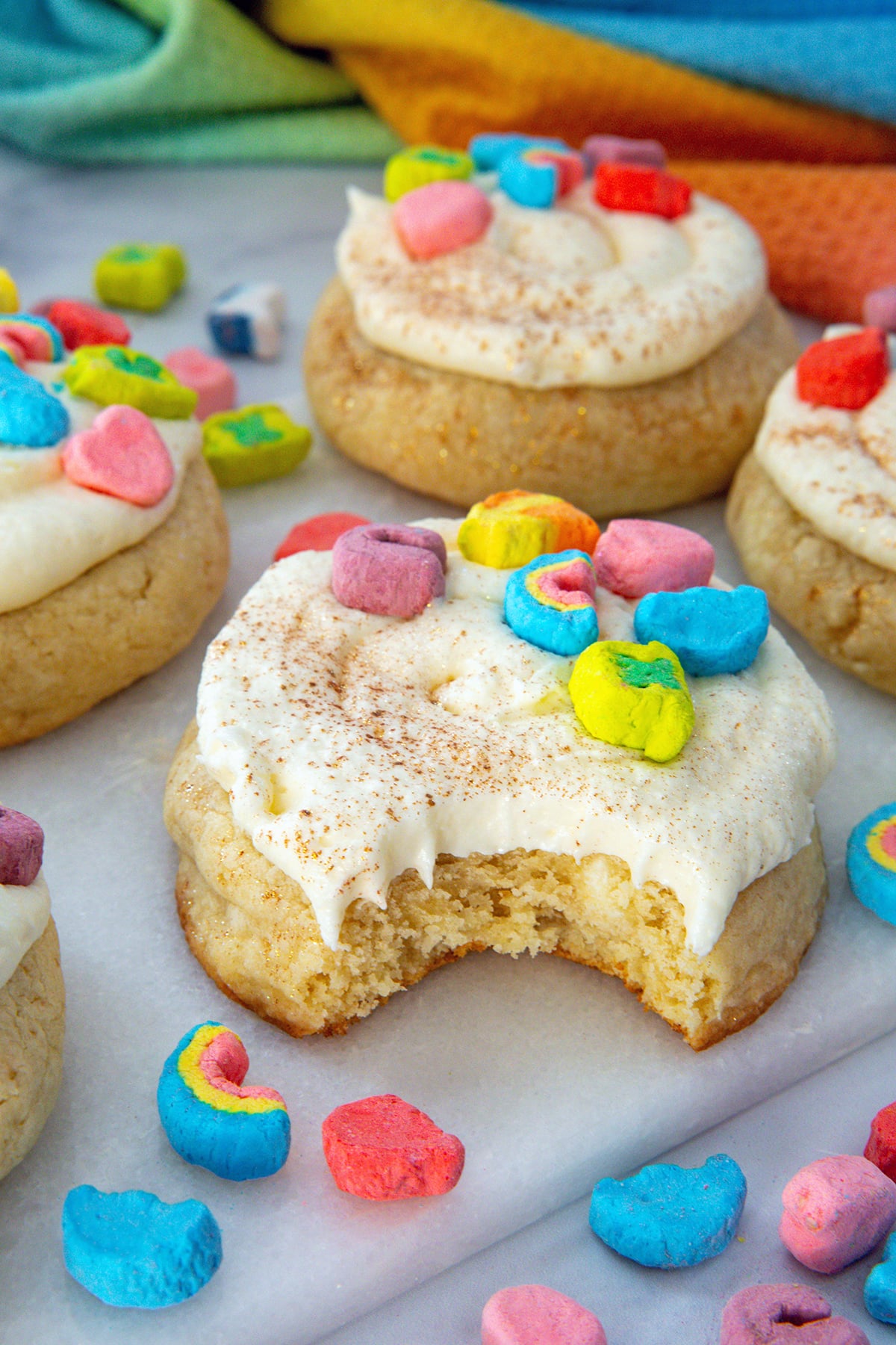 Closeup view of a Lucky Charms cookie with bite taken out of it, topped with colorful marshmallows.