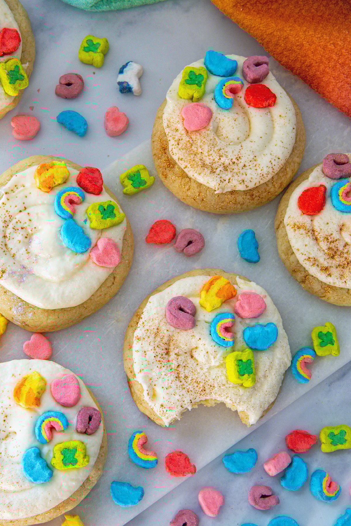Overhead view of Lucky Charms cookies with frosting and cereal marshmallows all around.