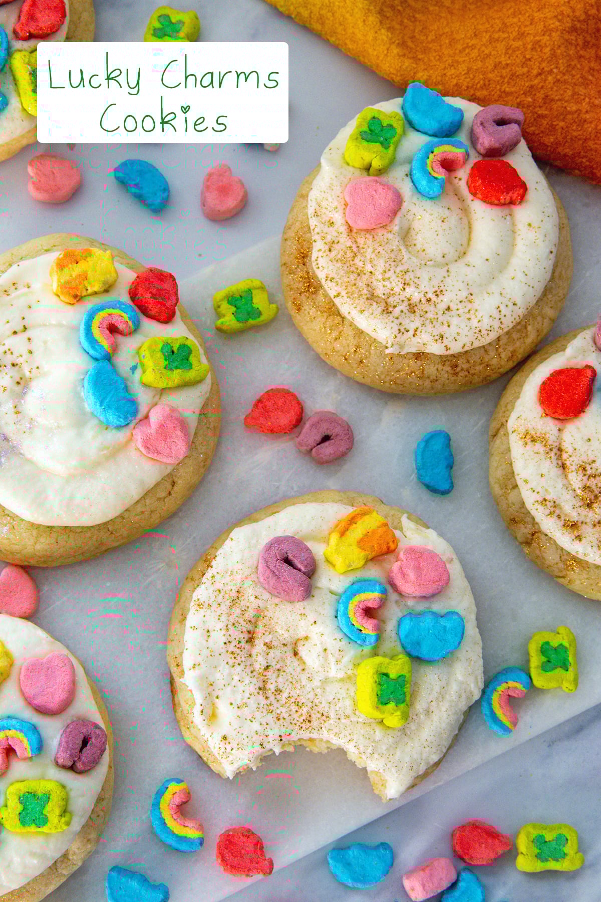 Overhead view of Lucky Charms cookies with frosting and cereal marshmallows all around with recipe title at top.