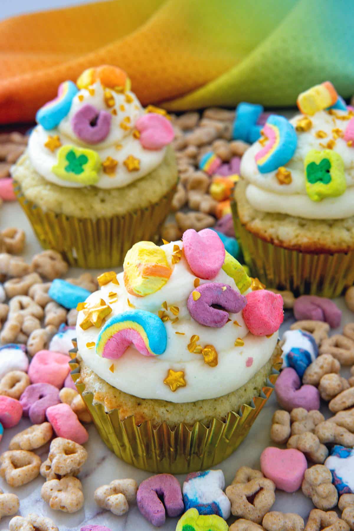Closeup view of a Lucky Charms cupcake surrounded by cereal.