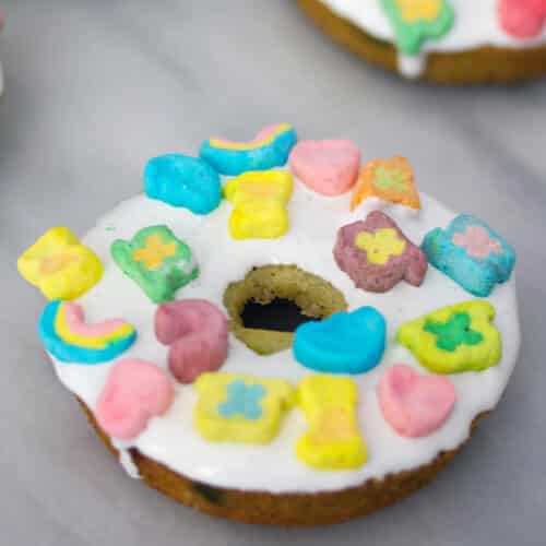 Closeup view of a Lucky Charms donut with marshmallow frosting and mini marshmallows on top.