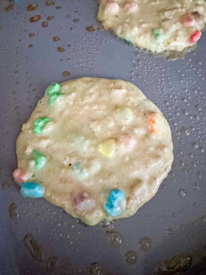 Lucky Charms pancake batter cooking on griddle.