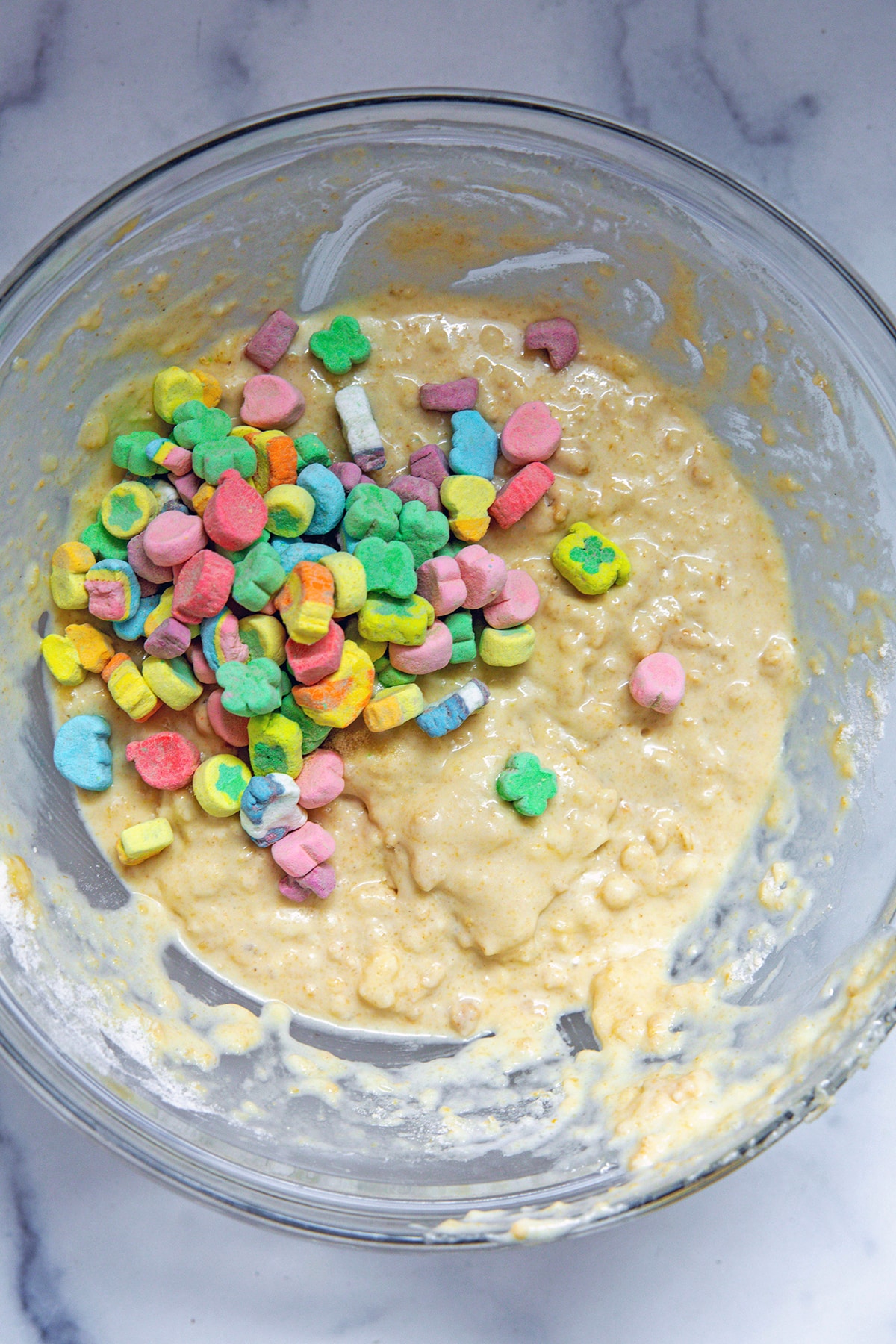 Pancake batter in mixing bowl with Lucky Charms marshmallows being mixed in.