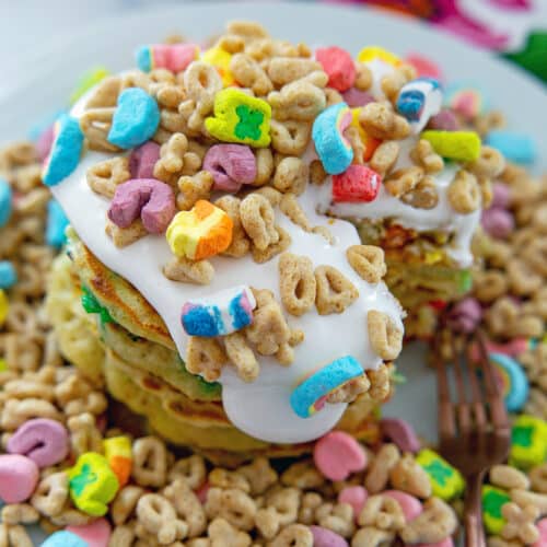 Closeup view of Lucky Charms pancakes with lots of marshmallow sauce and cereal.