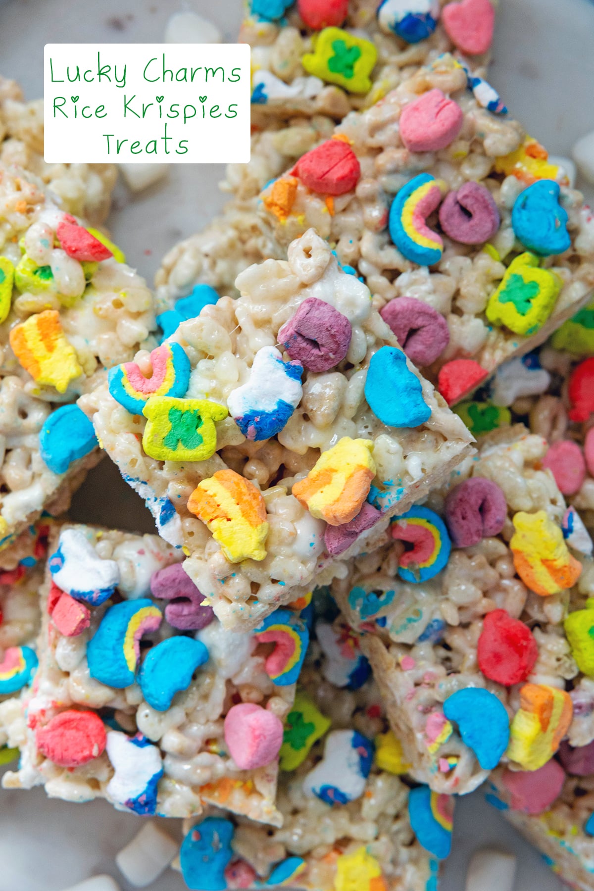 Overhead closeup view of a Lucky Charms Rice Krispies treat with colorful marshmallows with recipe title at top.