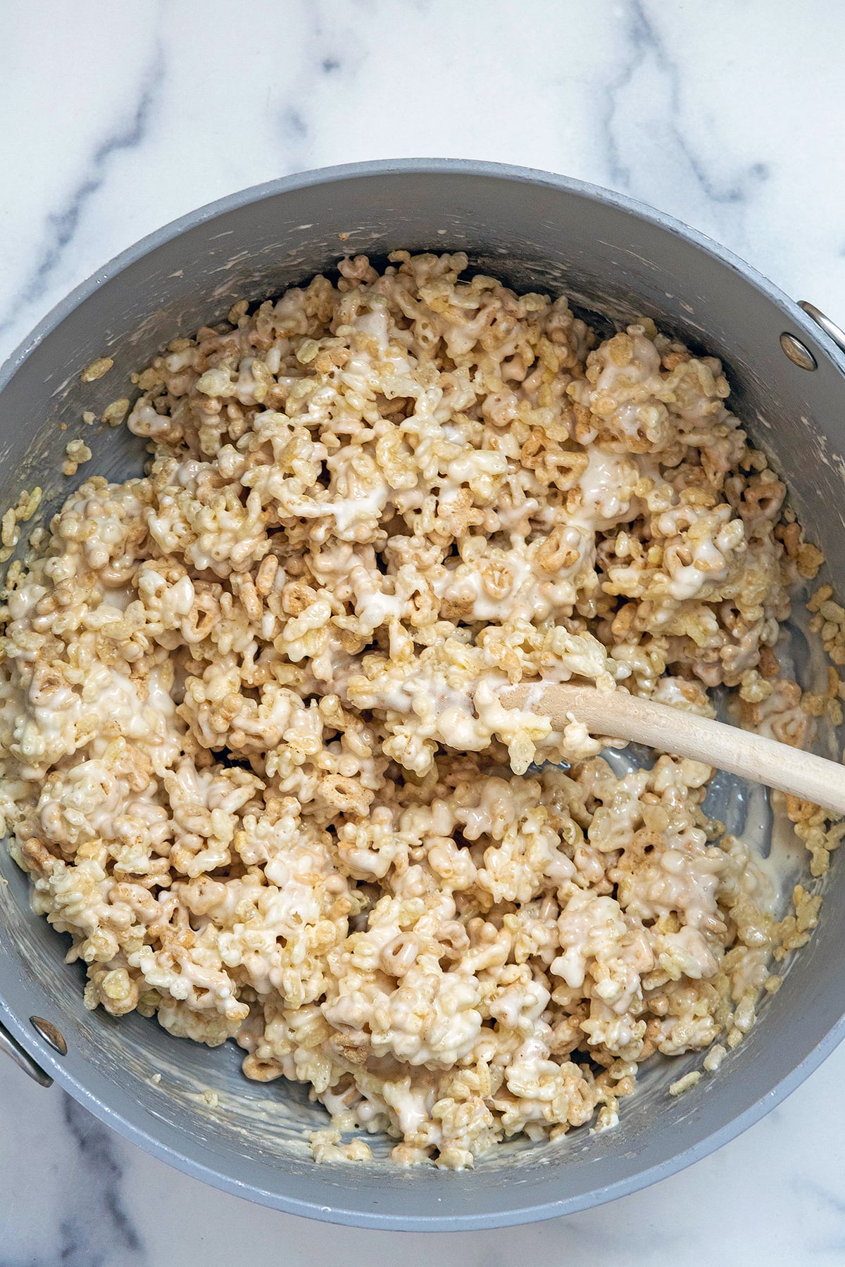 Overhead view of Rice Krispies and Lucky Charms oats cereal in saucepan with melted marshmallows.