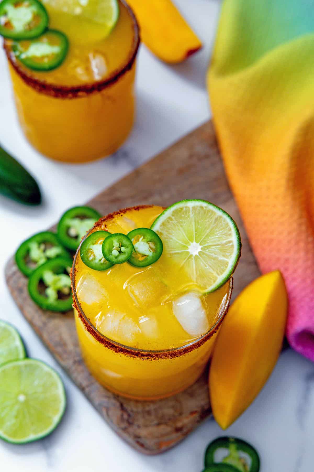 Overhead view of a mango jalapeño margarita with lime and jalapeño garnish.