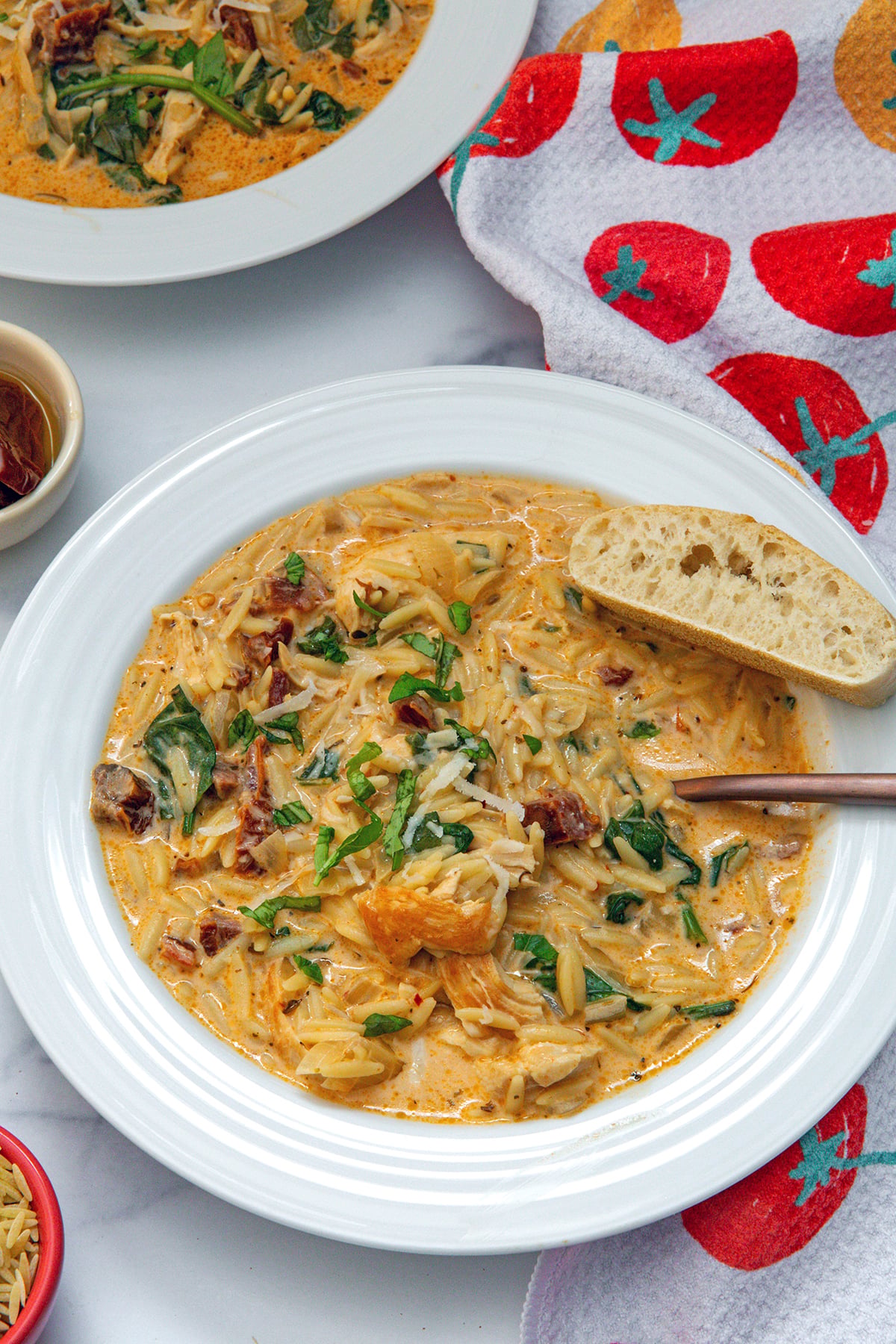 Closeup view of Marry Me Chicken Soup in bowl with spoon and slice of bread on side.