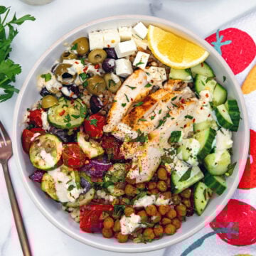 Closeup view of a Mediterranean grain bowl with chicken and veggies.