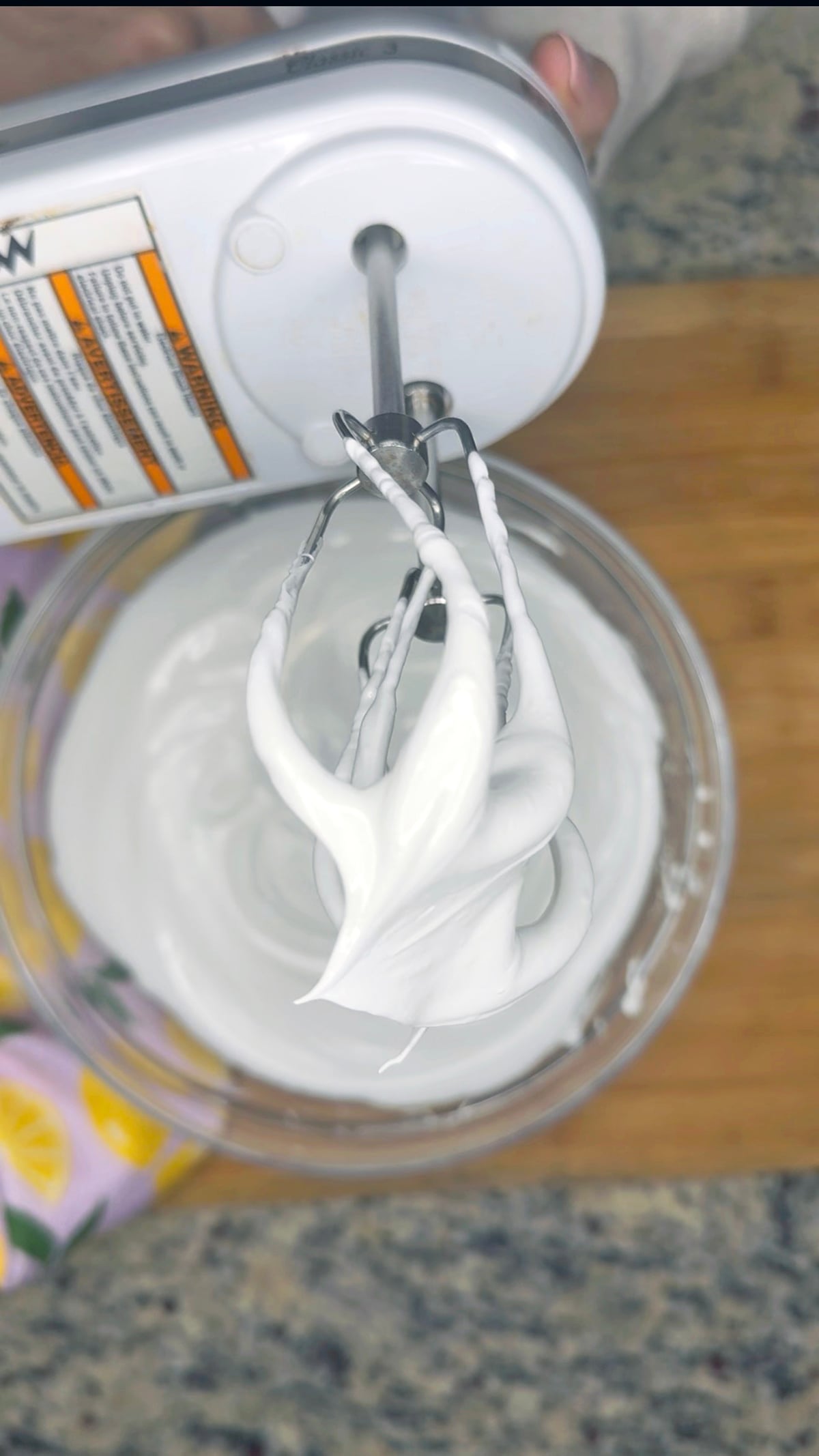 Stiff meringue peaks on a hand mixer whisk.