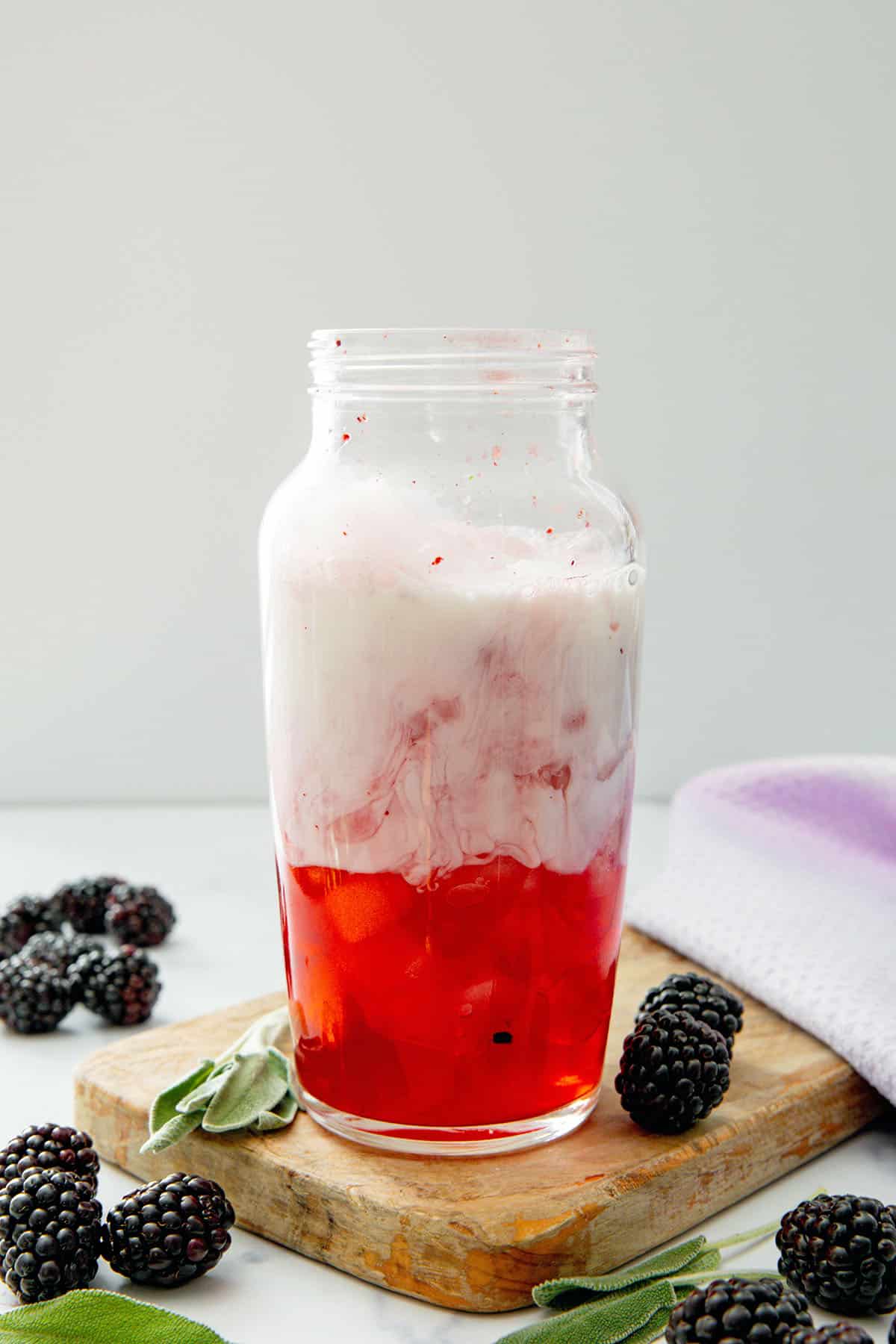 Blackberry sage drink base and coconut milk in a clear shaker.