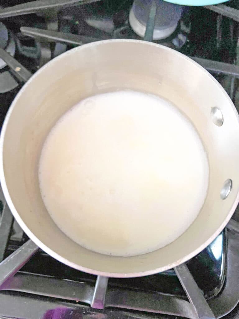 Milk and cream warming in saucepan on stove.