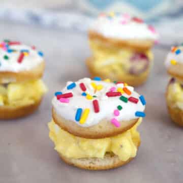 Closeup view of a mini donut egg salad sandwich with sprinkles and more in the background.