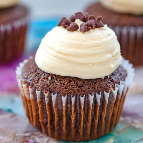 Closeup view of a mint chocolate chip cupcake with Baileys frosting and chocolate chips on top.
