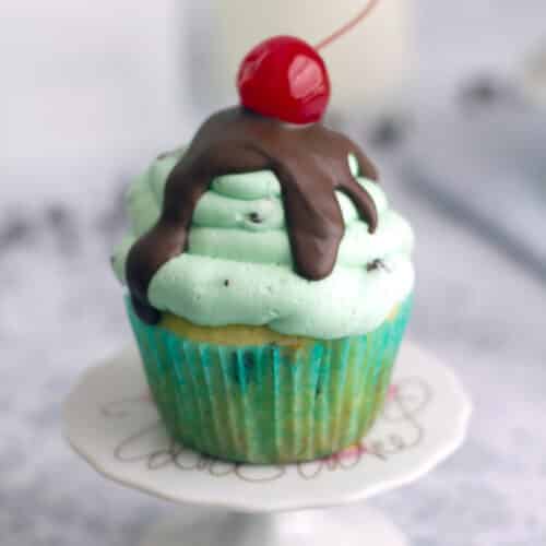 Closeup view of a mint chocolate chip ice cream cupcake with cherry on top.
