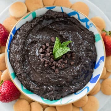 Closeup view of a bowl of mint chocolate hummus with Nilla Wafers and strawberries around it.