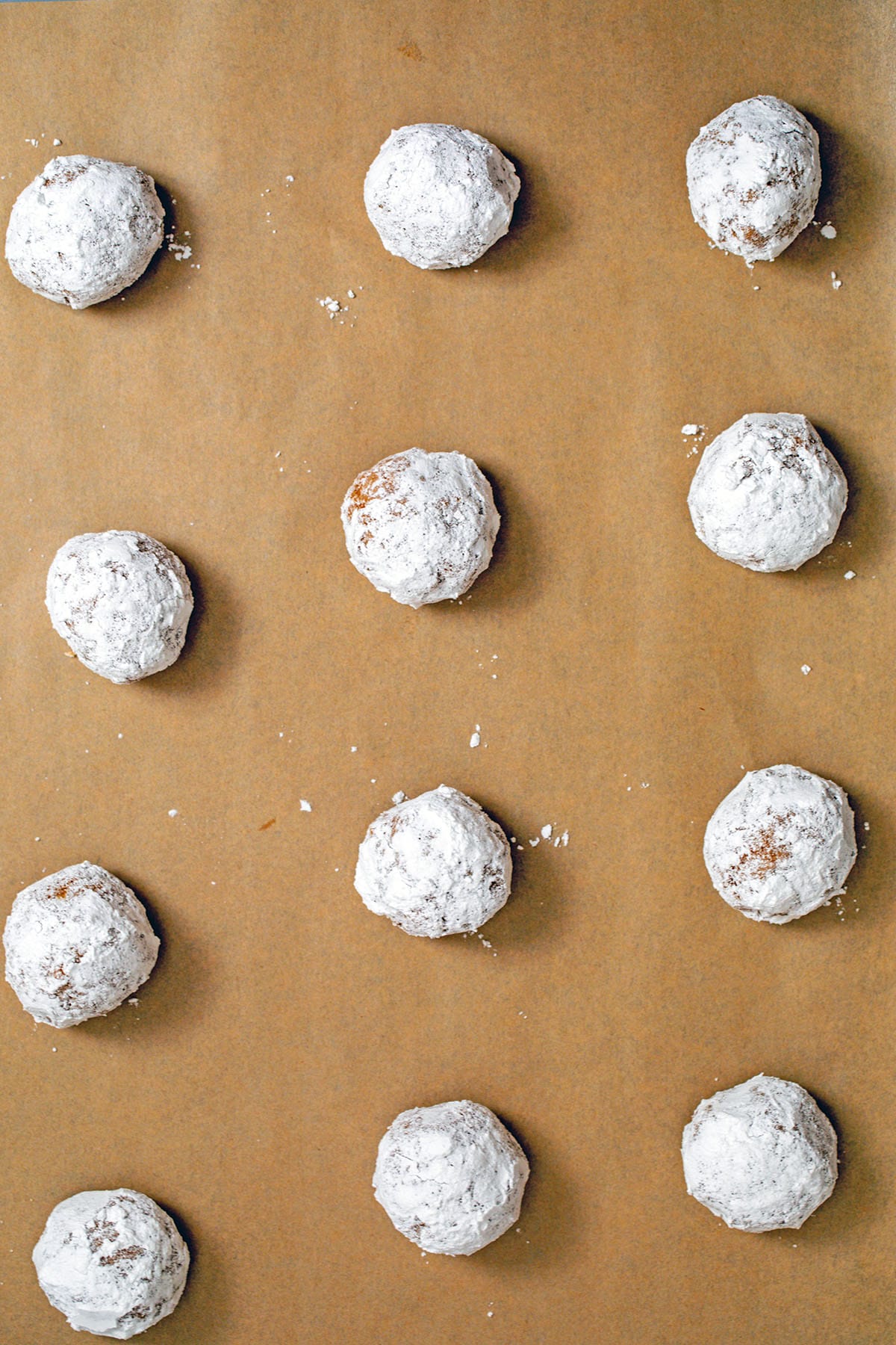 Confectioners' sugar rolled cookie dough balls on baking sheet.